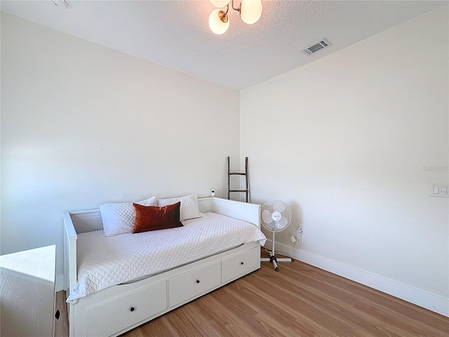 bedroom with light hardwood / wood-style flooring and a textured ceiling