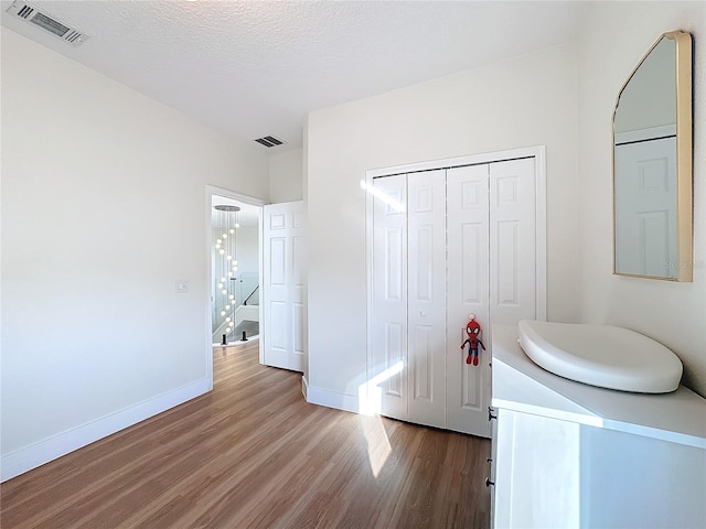 unfurnished bedroom featuring hardwood / wood-style flooring, a closet, and a textured ceiling