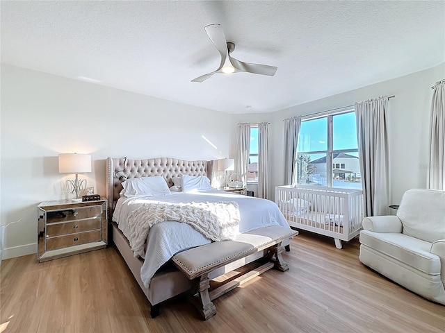 bedroom with ceiling fan, light hardwood / wood-style floors, and a textured ceiling