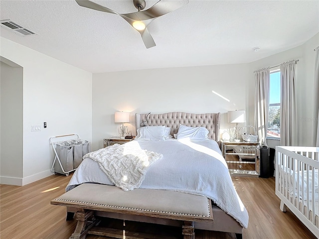 bedroom featuring ceiling fan, light hardwood / wood-style floors, and a textured ceiling