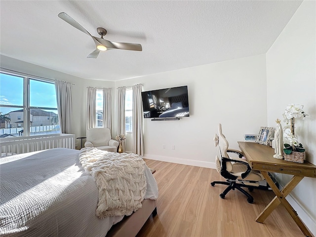 bedroom featuring ceiling fan, light hardwood / wood-style floors, and a textured ceiling