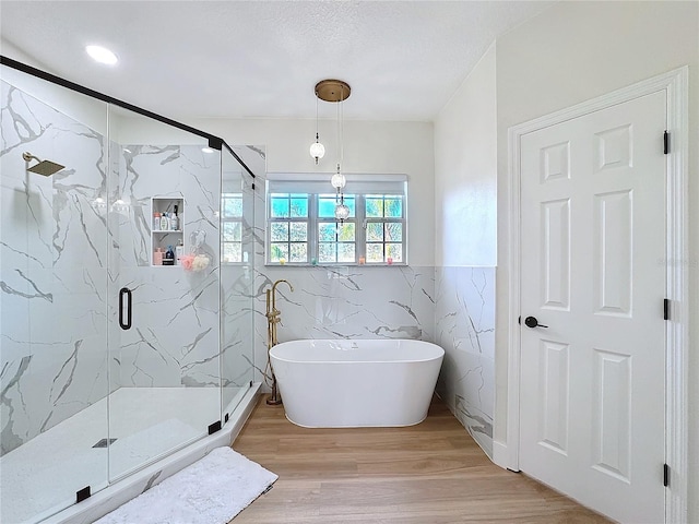 bathroom featuring shower with separate bathtub, hardwood / wood-style floors, a textured ceiling, and tile walls