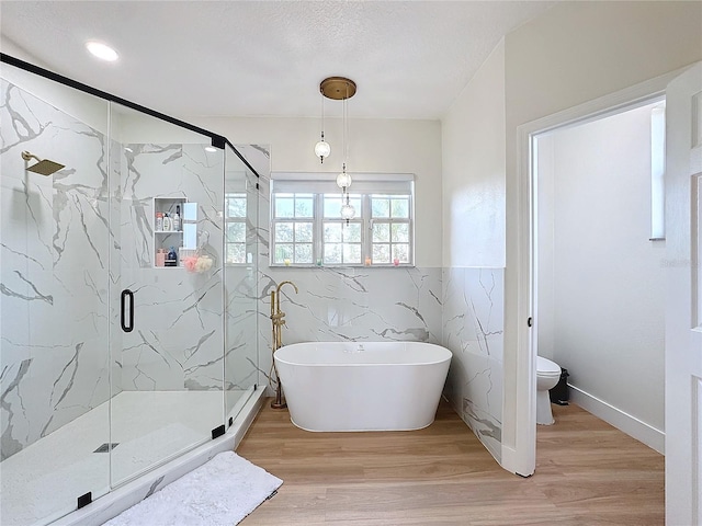 bathroom with tile walls, wood-type flooring, independent shower and bath, and toilet