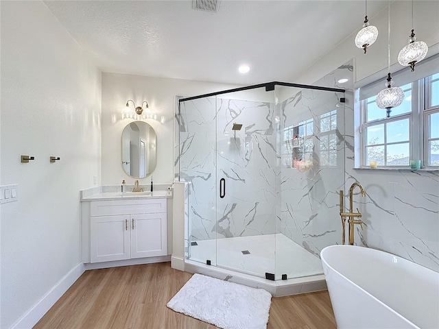 bathroom featuring wood-type flooring, shower with separate bathtub, and vanity