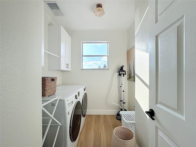 washroom featuring cabinets, separate washer and dryer, and light hardwood / wood-style floors