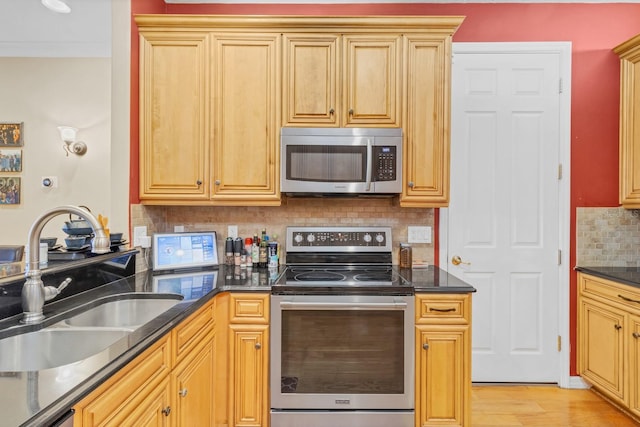 kitchen featuring appliances with stainless steel finishes, sink, decorative backsplash, crown molding, and light wood-type flooring