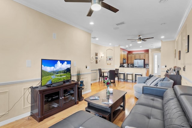 living room featuring crown molding, ceiling fan, and light hardwood / wood-style floors