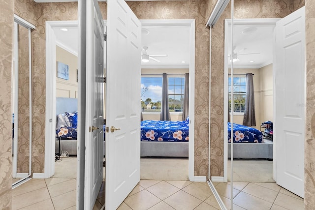 hall featuring light tile patterned floors and ornamental molding