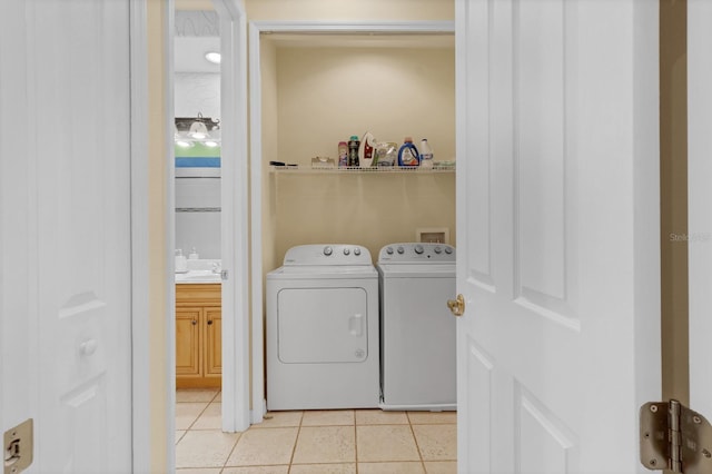 clothes washing area with light tile patterned flooring, independent washer and dryer, and sink