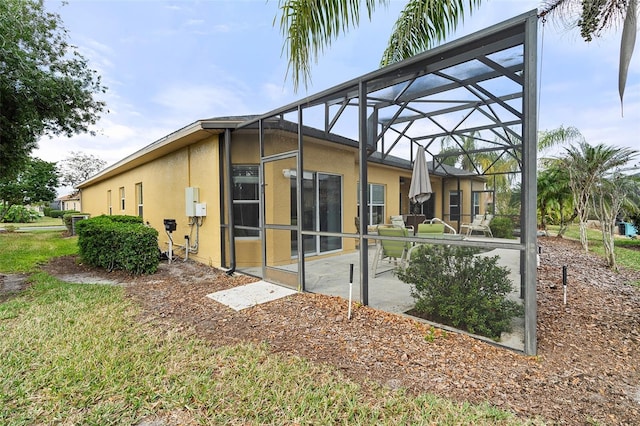 back of property featuring glass enclosure and a patio area