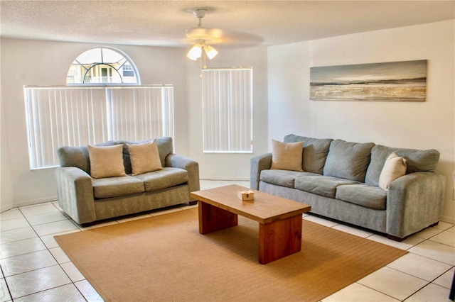 living room with light tile patterned flooring, ceiling fan, and a textured ceiling