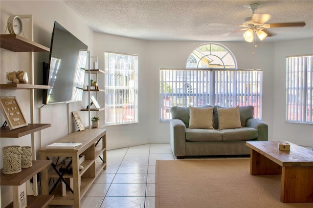 living room featuring ceiling fan, light tile patterned floors, and a textured ceiling