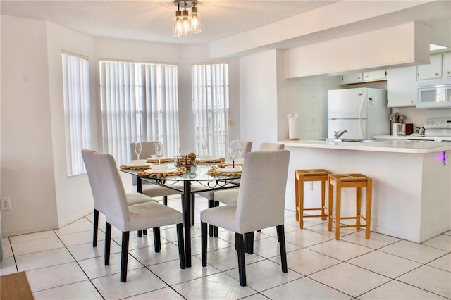 tiled dining area featuring sink and a textured ceiling