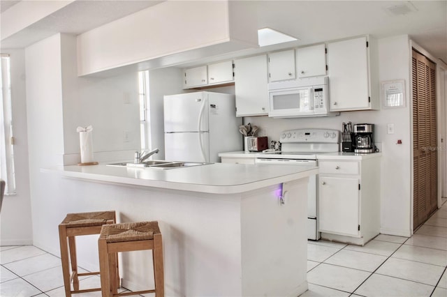 kitchen with sink, a breakfast bar area, white cabinetry, light tile patterned floors, and white appliances