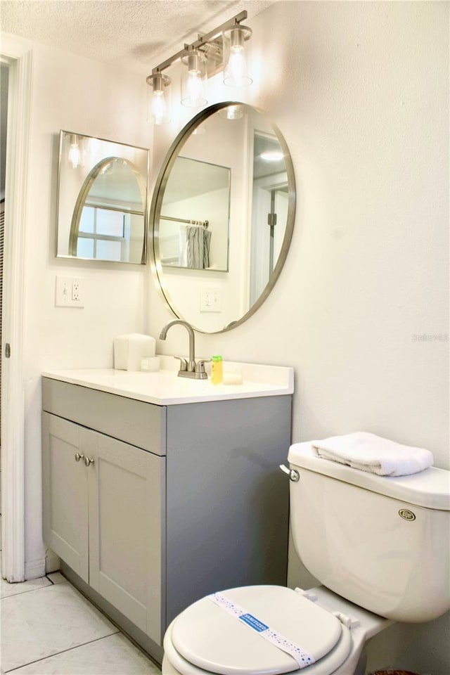 bathroom with vanity, toilet, tile patterned flooring, and a textured ceiling