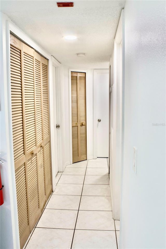 hallway with light tile patterned floors and a textured ceiling