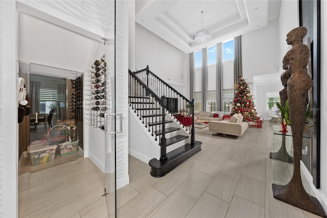 interior space featuring an inviting chandelier, a towering ceiling, and a raised ceiling