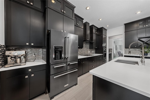 kitchen featuring sink, tasteful backsplash, black appliances, a textured ceiling, and wall chimney range hood