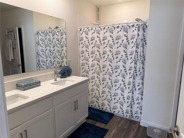 bathroom with double vanity, wood finished floors, a sink, and a shower with curtain