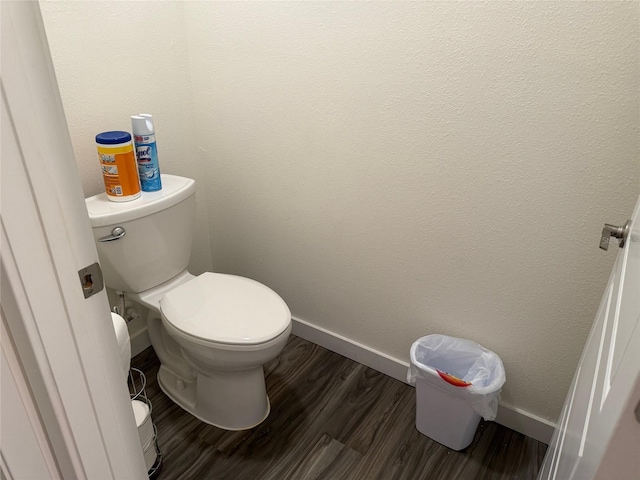 bathroom with toilet, baseboards, and wood finished floors