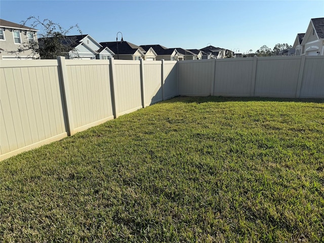 view of yard featuring a fenced backyard and a residential view