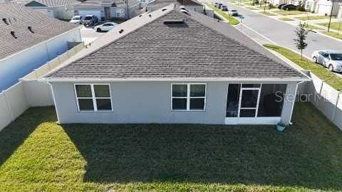 back of house featuring a yard, a shingled roof, and fence private yard