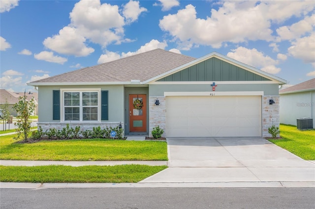 view of front of property with cooling unit, a garage, driveway, stone siding, and a front yard