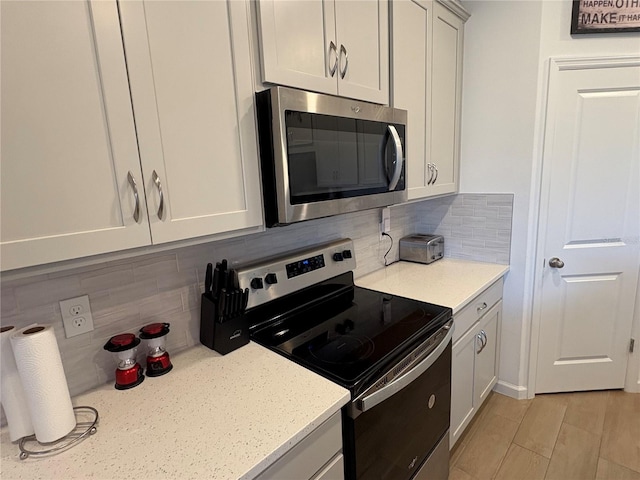 kitchen with stainless steel appliances, light stone countertops, light wood-type flooring, and backsplash