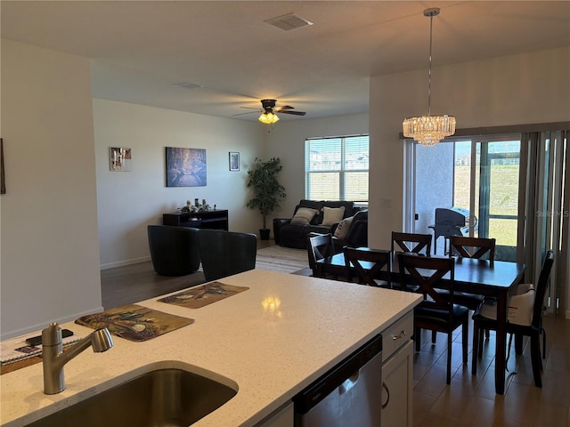 kitchen featuring pendant lighting, sink, dishwasher, light stone countertops, and ceiling fan with notable chandelier