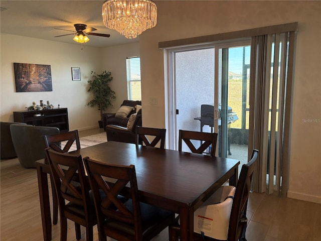 dining space featuring ceiling fan with notable chandelier and light hardwood / wood-style floors