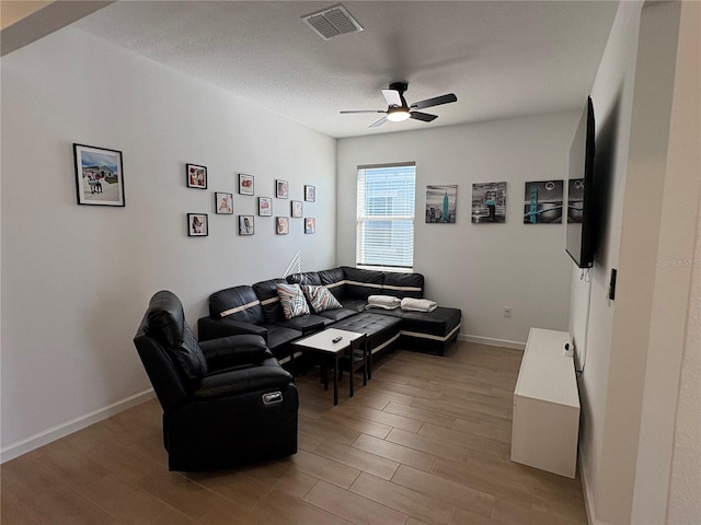 living room featuring wood-type flooring, a textured ceiling, and ceiling fan