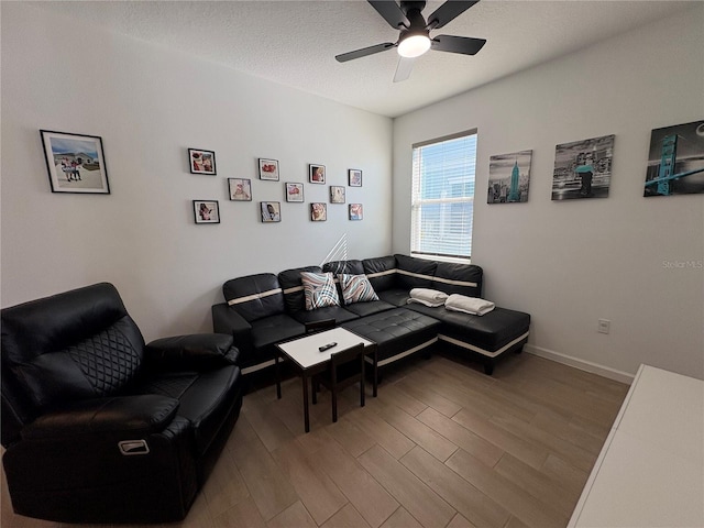 living room featuring ceiling fan, wood-type flooring, and a textured ceiling