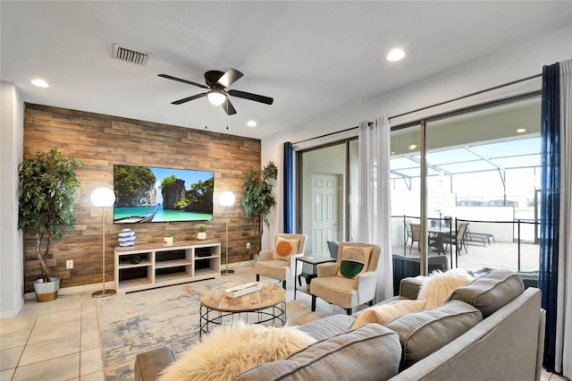 living room with ceiling fan, light tile patterned floors, and wood walls