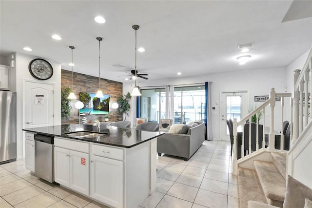 kitchen with sink, a center island with sink, light tile patterned floors, appliances with stainless steel finishes, and white cabinets