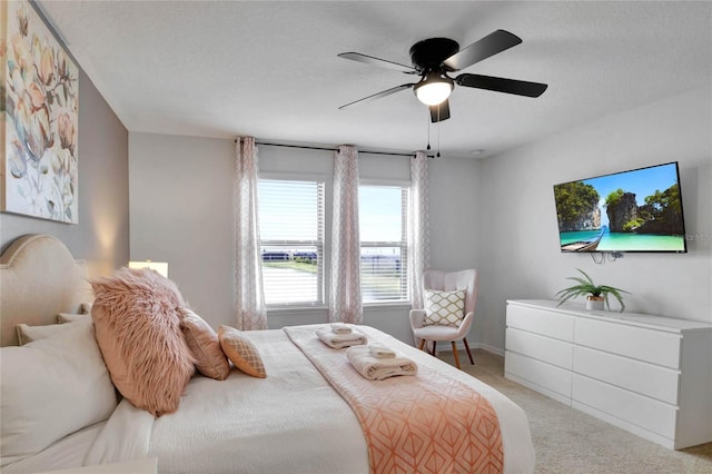 bedroom with ceiling fan, light carpet, and a textured ceiling