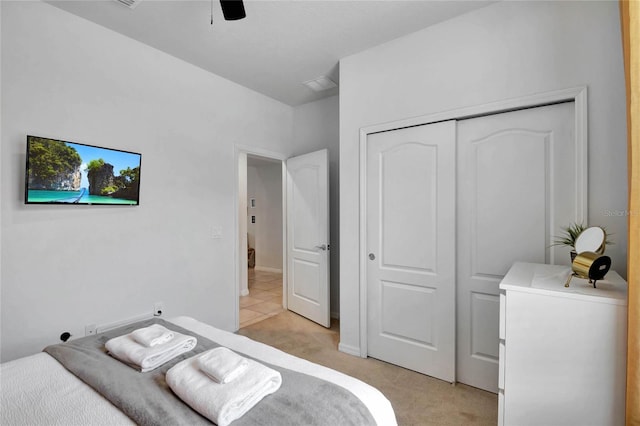 bedroom with light colored carpet, ceiling fan, and a closet