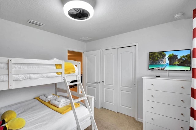 bedroom featuring light colored carpet, a closet, and a textured ceiling