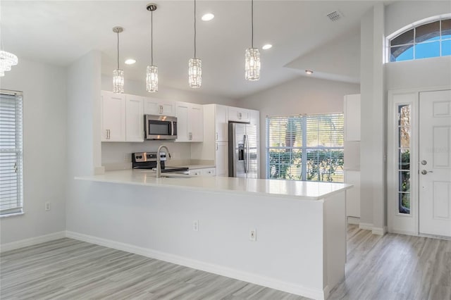 kitchen with pendant lighting, light hardwood / wood-style flooring, white cabinetry, stainless steel appliances, and kitchen peninsula