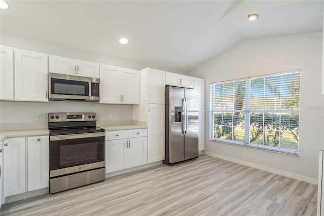 kitchen with white cabinetry, stainless steel appliances, vaulted ceiling, and light hardwood / wood-style flooring