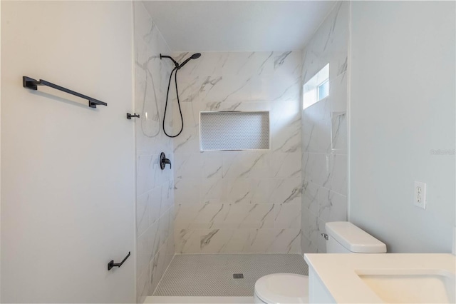 bathroom featuring vanity, toilet, and tiled shower