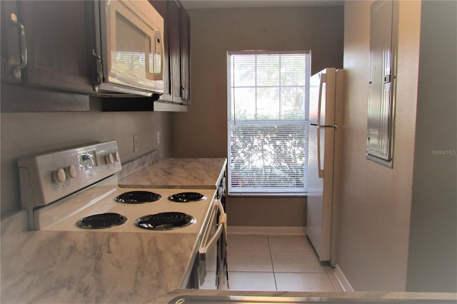 kitchen with light tile patterned floors, white appliances, baseboards, and light stone countertops