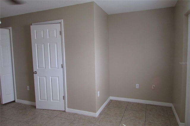 spare room featuring light tile patterned flooring and baseboards