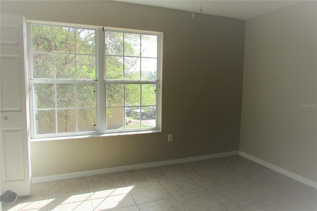 unfurnished room featuring light tile patterned floors, a healthy amount of sunlight, and baseboards