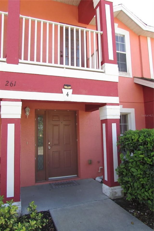 entrance to property with stucco siding and a balcony