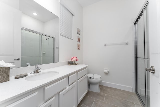 bathroom with vanity, a shower with shower door, tile patterned floors, and toilet