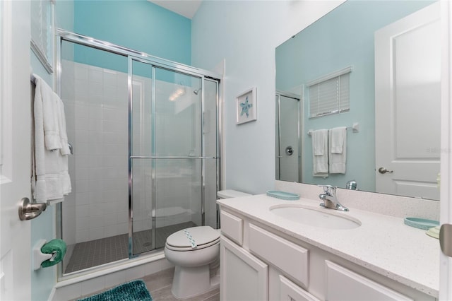 bathroom featuring vanity, a shower with shower door, and toilet