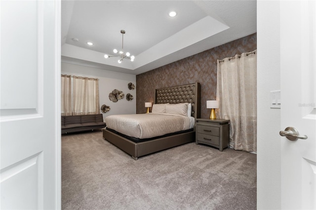 carpeted bedroom featuring a raised ceiling and a chandelier