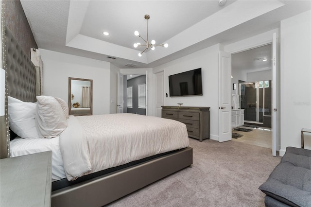 bedroom with an inviting chandelier, light colored carpet, connected bathroom, and a tray ceiling