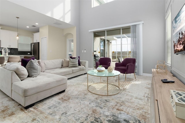 tiled living room featuring sink and a high ceiling