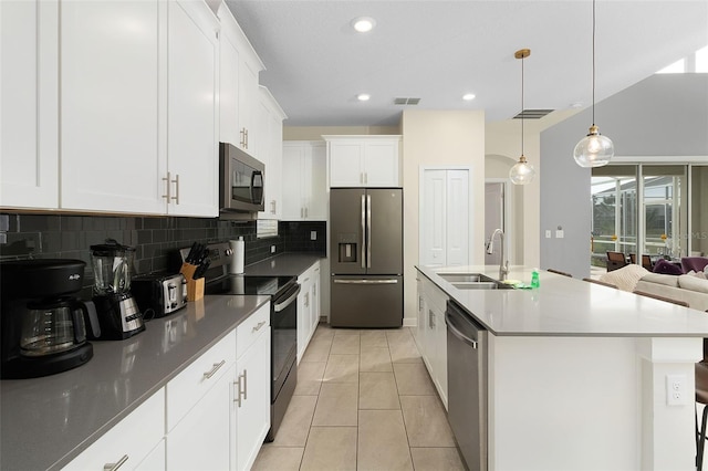 kitchen featuring sink, appliances with stainless steel finishes, white cabinetry, a kitchen island with sink, and decorative light fixtures